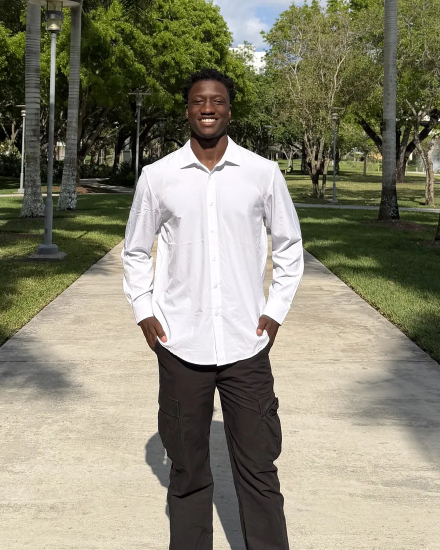 Boubacar Diatta smiling in a white shirt on a palm-lined walkway